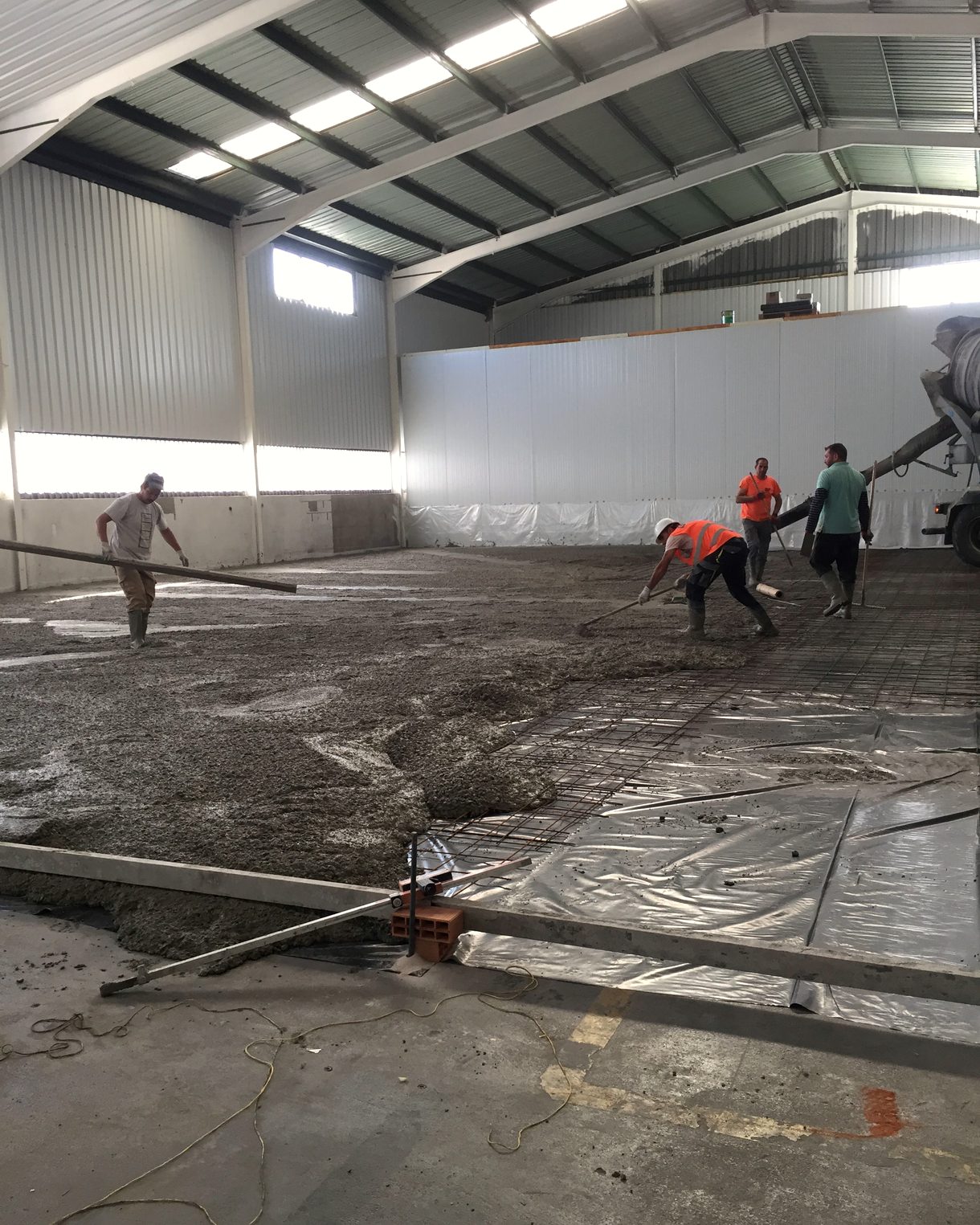 Operarios extendiendo el pavimento de una nave